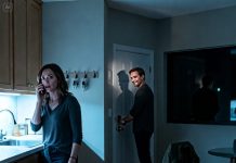 The bank called, panicked: “Who do you think you’re living with?” I looked at the man locking the door like always. “What’s wrong?” he asked calmly. “He looks identical,” the voice shook, “but the real one died years ago.” I hung up, heart racing. When I looked back—his smile hadn’t changed. And I knew… tonight, the truth wouldn’t let anyone sleep.