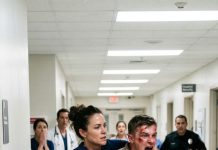 The ER doors burst open as a towering 7-foot man stormed inside, shouting and hurling chairs while terrified staff backed away. Security lingered at a distance. Doctors froze. No one wanted to face him. Then a young rookie nurse quietly stepped forward. She didn’t shout. She didn’t run. Seconds later, the chaos ended—and the giant was on the floor while the entire emergency room stood in stunned silence.