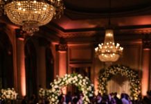 Everything was perfect at my wedding until the photographer quietly grabbed my arm and said, “Look at your phone. Stay calm.” I opened a message from an unknown number showing a photo of me walking down the aisle. The text beneath it made my heart stop—because whoever sent it wasn’t outside… they were somewhere inside the wedding watching me.